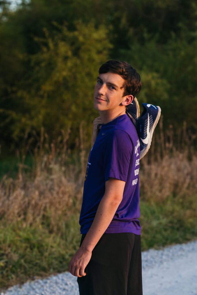 Senior cross country runner photos with shoes in rustic outdoor setting near Kansas City