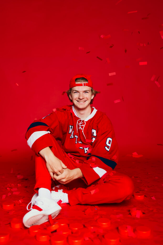 High school boy in his hockey jersey with red background in the studio