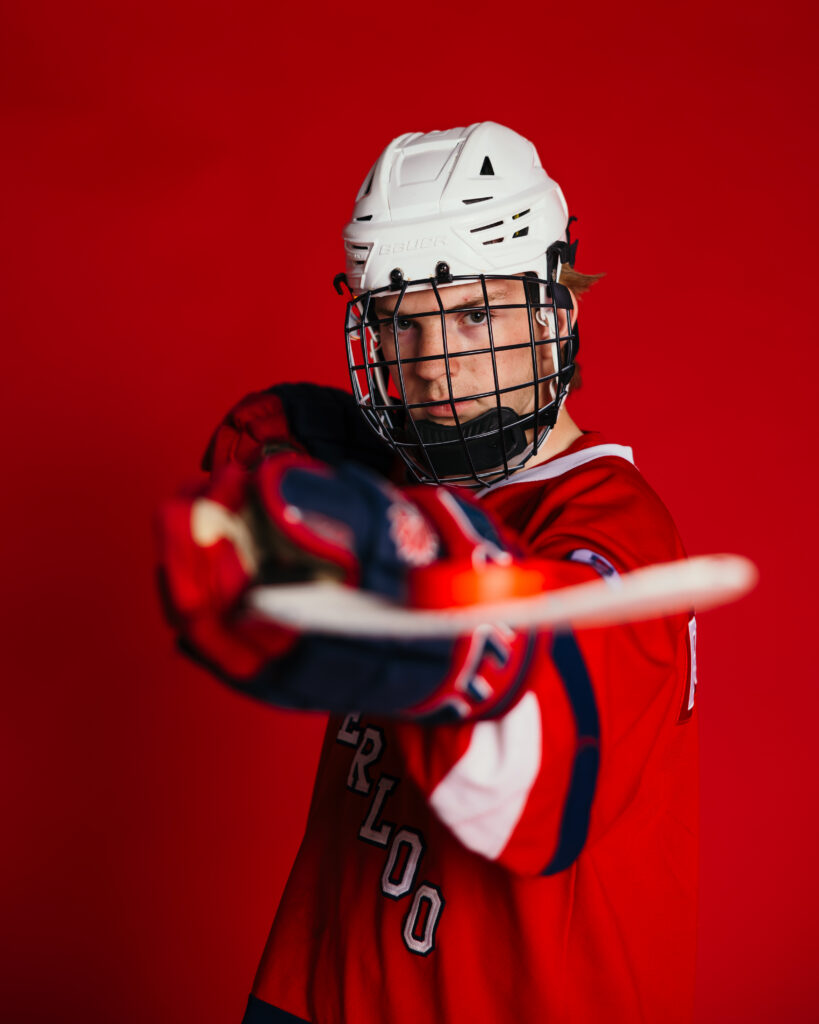 Senior portrait of Kansas City athlete holding hockey stick in modern studio setting