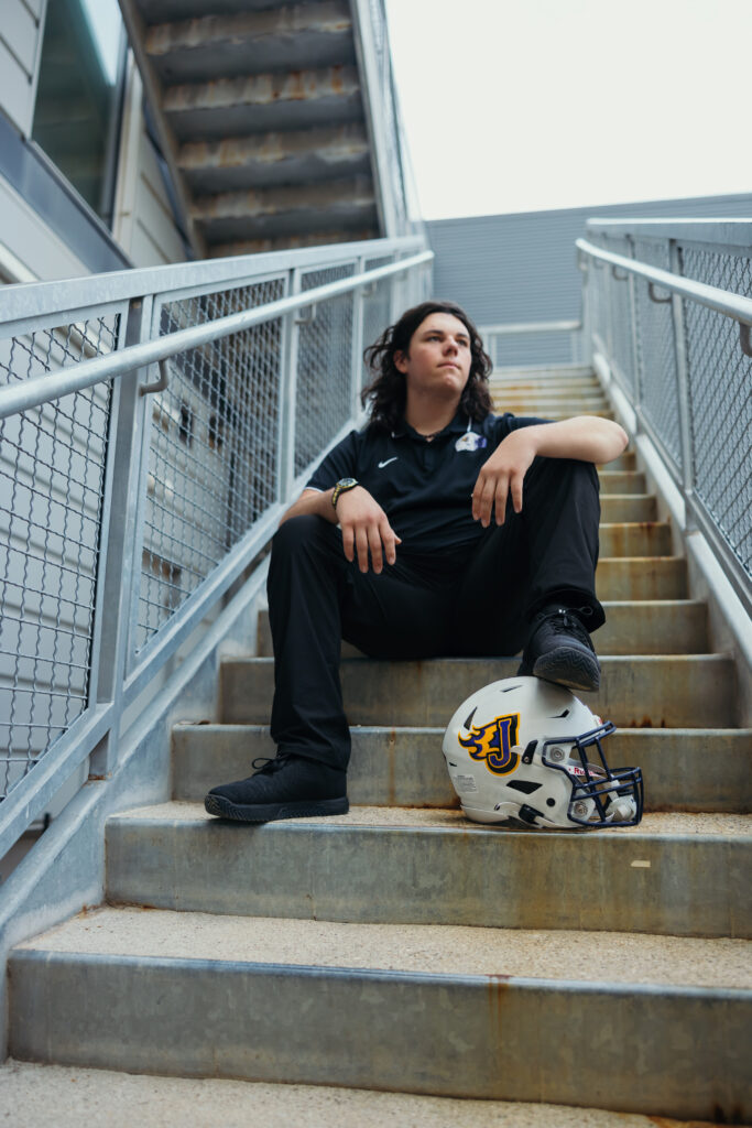 Male senior athlete photos in Kansas City with football gear and city backdrop