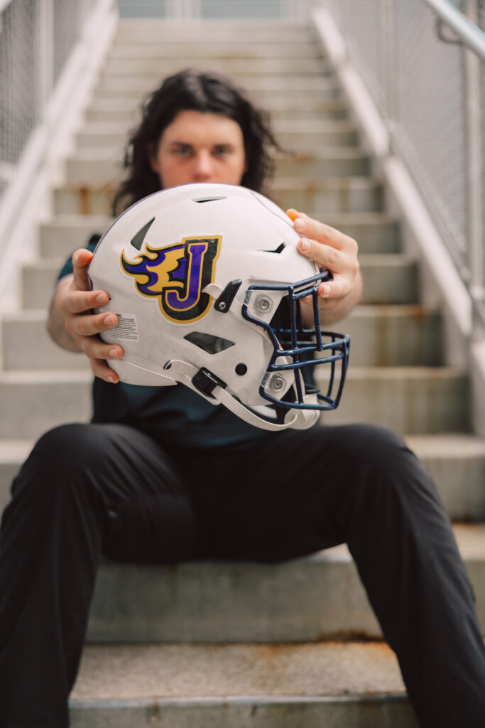 Kansas City senior boy holding football helmet in urban downtown location