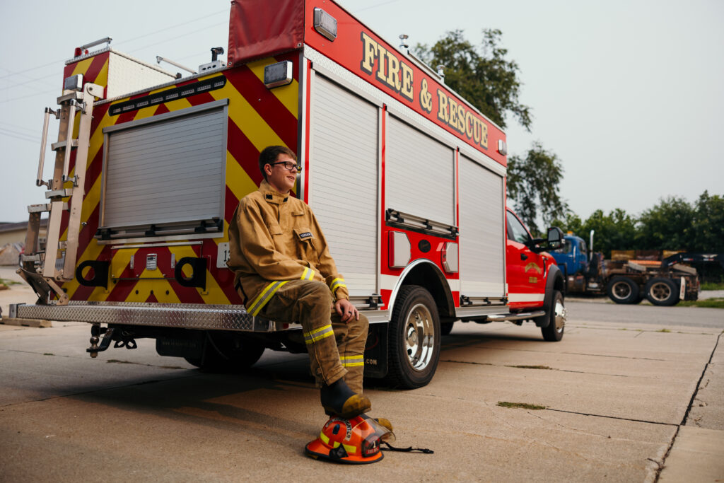 Senior boy posing beside fire truck during high school senior portraits