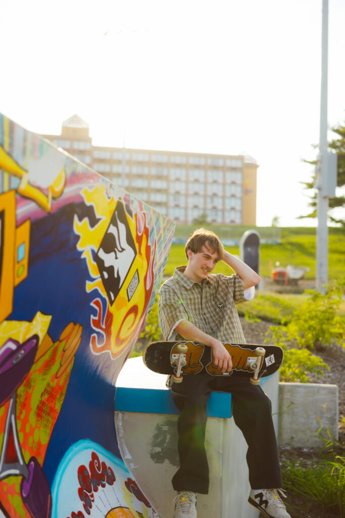 High school senior boy with skateboard at golden hour