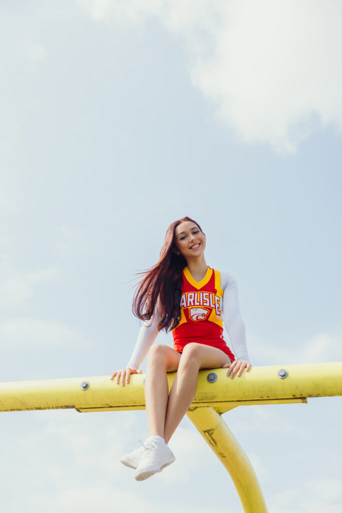 Kansas City senior cheerleader posing on high school football field during senior photo session