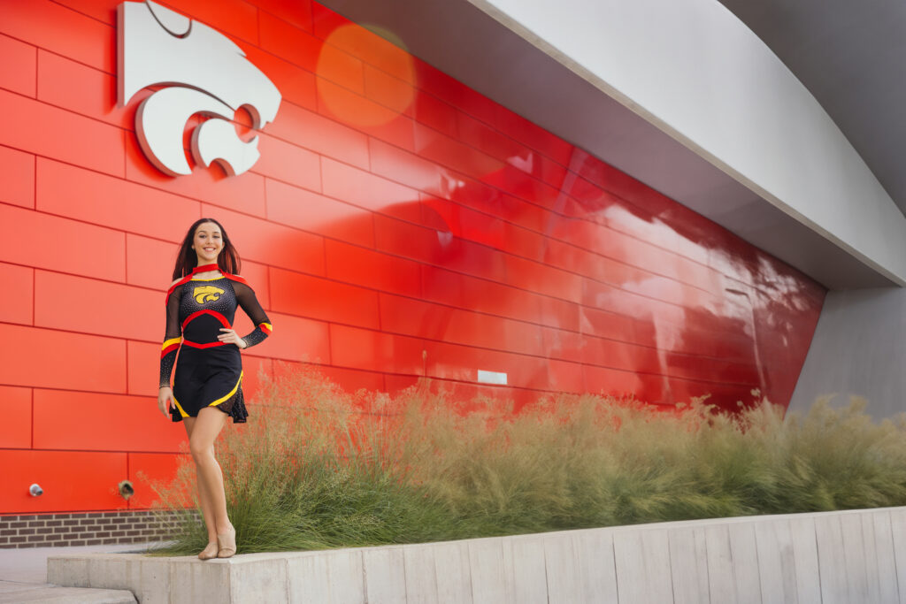 Kansas City senior girl in cheer uniform posing in front of stadium