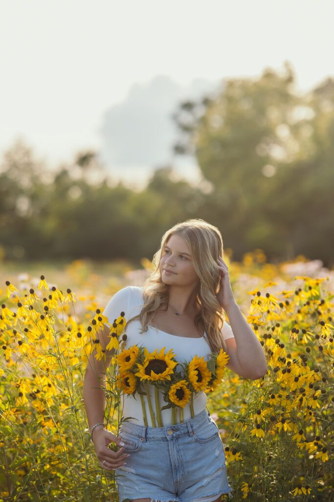 High school senior girl in wildflower field during golden hour