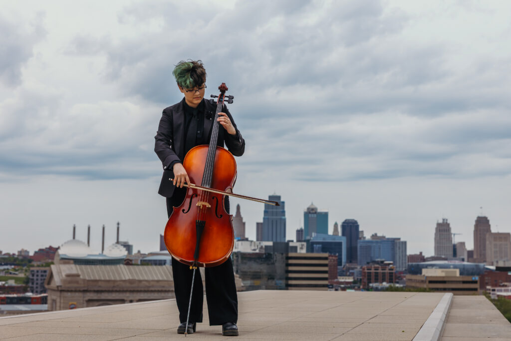 Kansas City high school senior photographed with cello in front of the KC skyline at Liberty Memorial