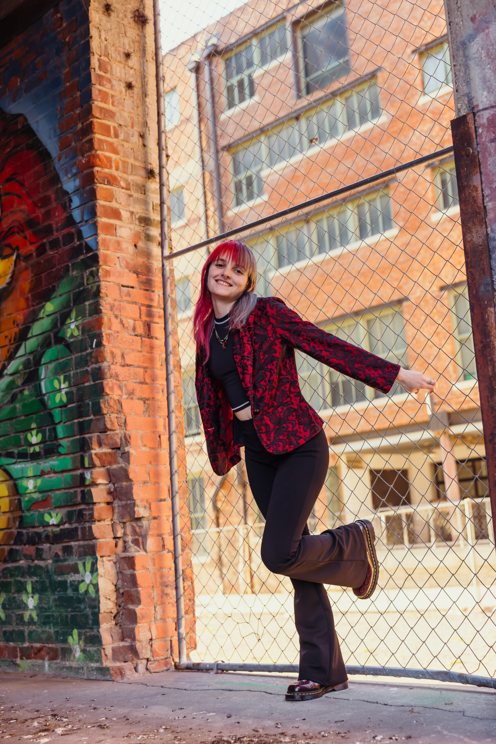 High school senior posing in urban Kansas City alley with colorful street art