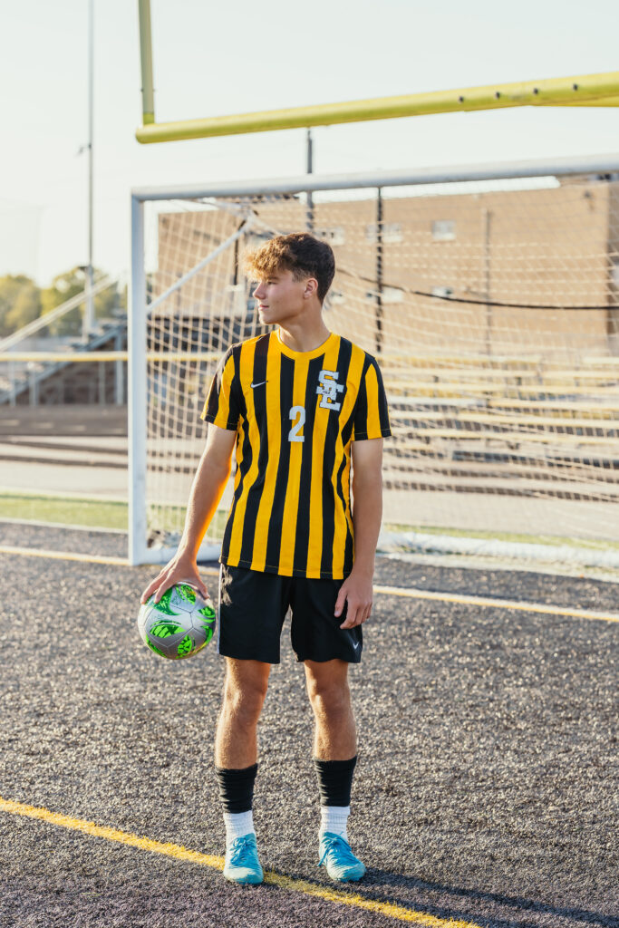 Kansas City senior boy posing on soccer field during athletic senior photo session