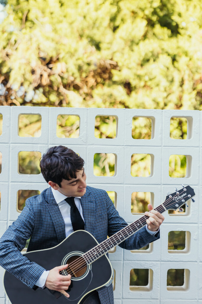 High school senior playing acoustic guitar during outdoor senior photos