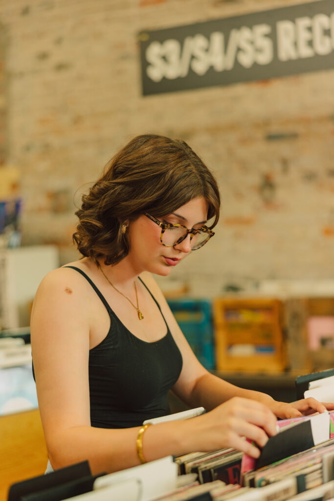 Senior girl browsing vinyl records at Mills Record Company in Kansas City senior portraits