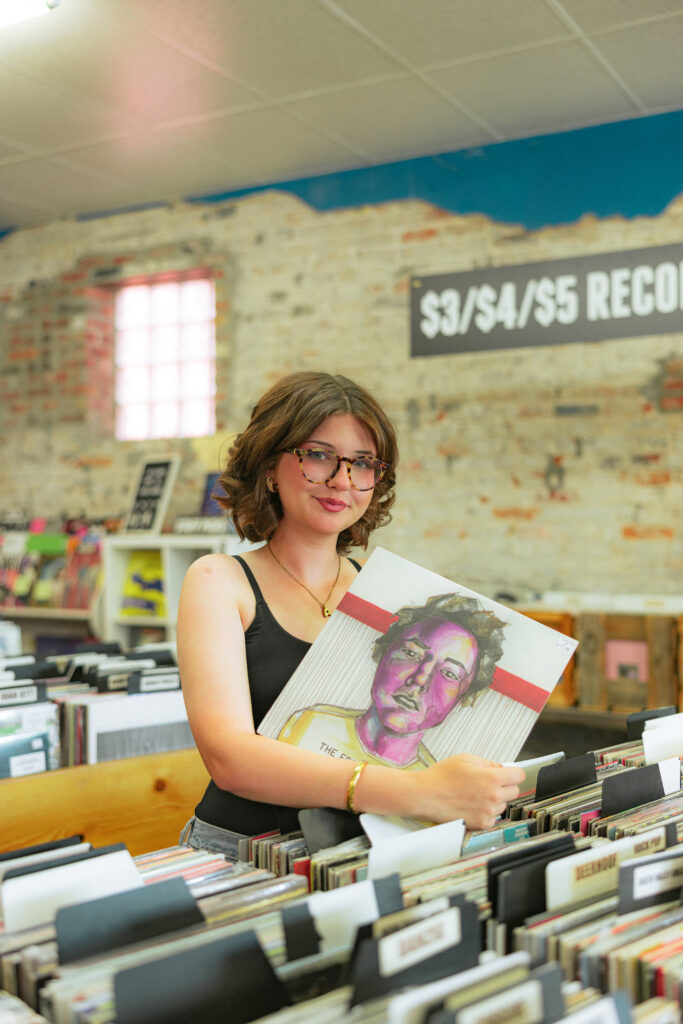 High school senior girl smiling inside Mills Record Company for unique Kansas City senior session