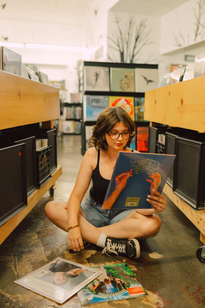 Creative Kansas City senior photos of high school senior girl in record shop with vinyl albums