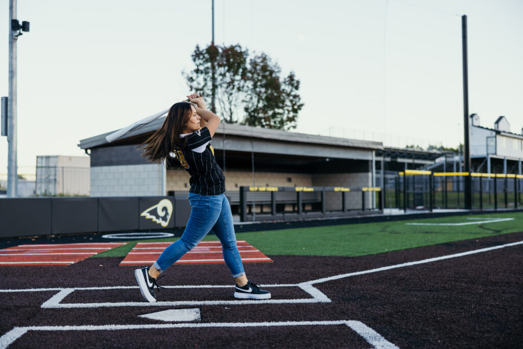 Senior girl playing softball during high school senior photo session