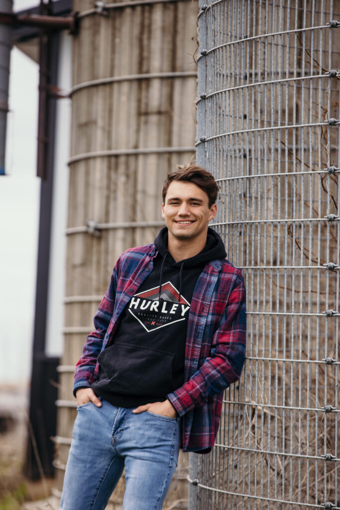 High school senior boy leaning against silo in the country