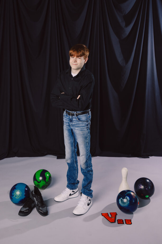 Kansas City senior boy posing in studio with bowling ball and bowling gear