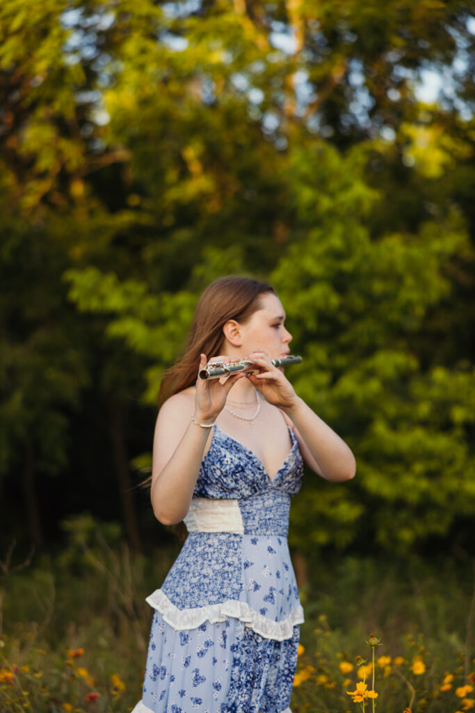 Kansas City senior portraits of senior girl with flute surrounded by wildflowers