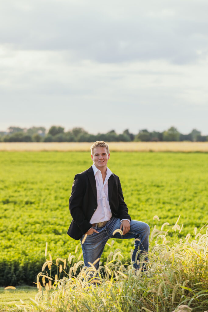 High school senior with suit jacket posing in an open field