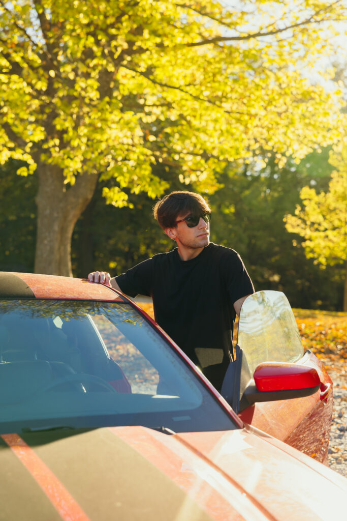 Senior boy posing with his car in sunglasses