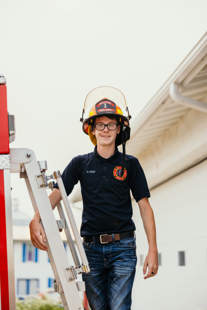 High school senior boy with fire hat on at fire station for senior session