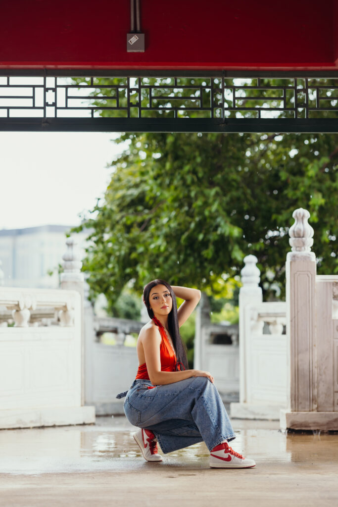 High school senior posing showing off red Nike shoes