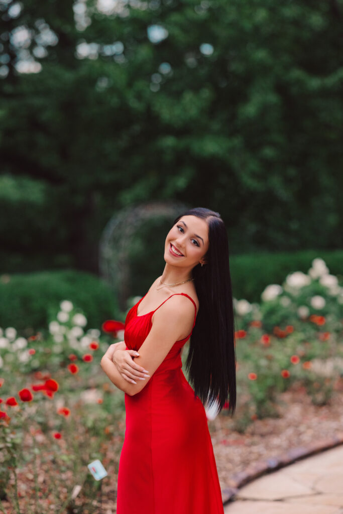High school senior photoshoot in rose garden with red silk dress