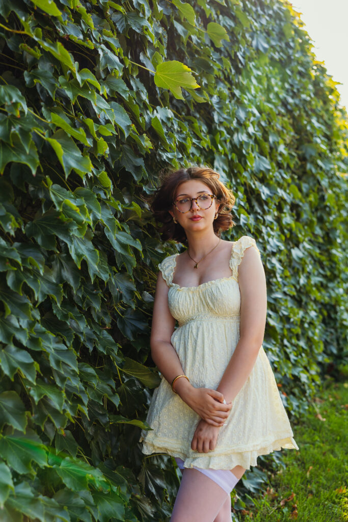 High school senior girl with ivy wall in light yellow ruffle dress