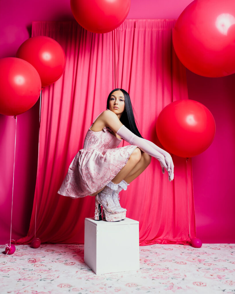 Pink studio session for high school senior girl with gloves, high heels, and balloons