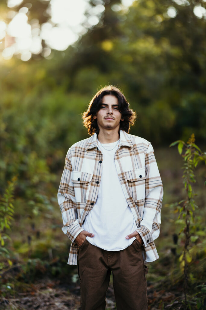 High school senior boy in browns and neutral colors during golden hour in nature setting