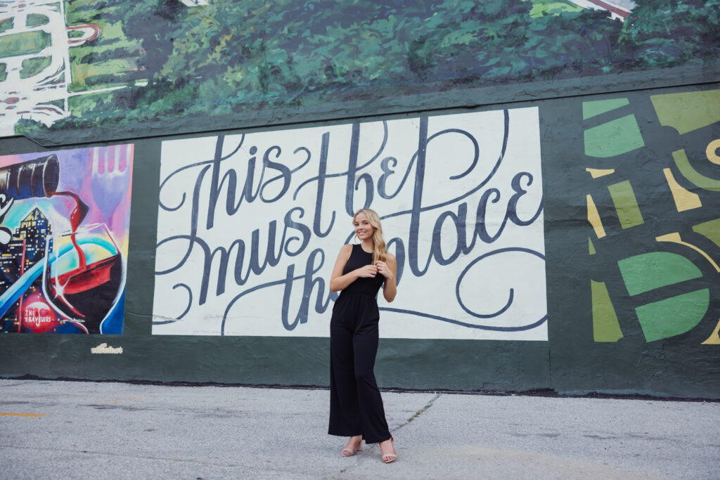 High school senior posing downtown with a wall mural