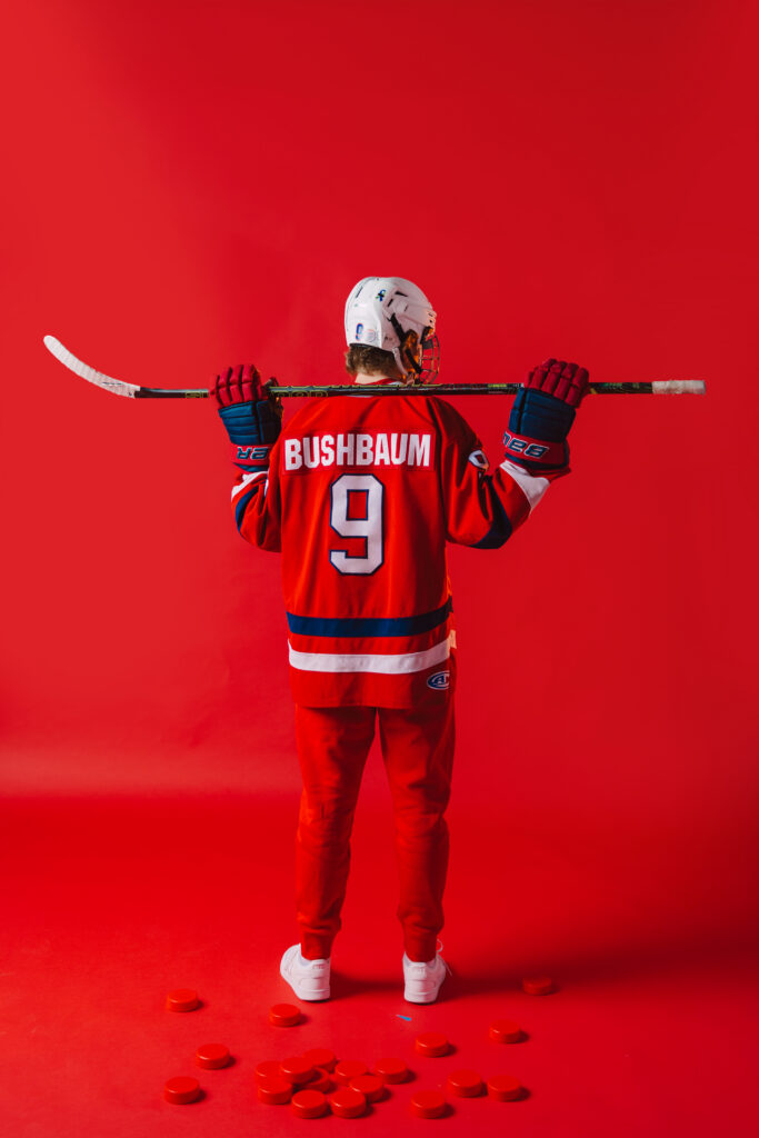 High school senior boy posing in hockey uniform with hockey stick