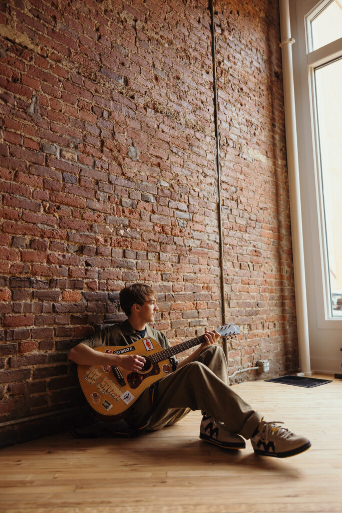 High school senior boy playing his guitar during senior photoshoot