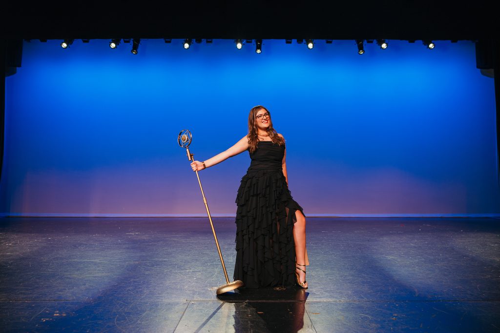 Kansas City senior portrait with a vintage microphone on her high school auditorium stage