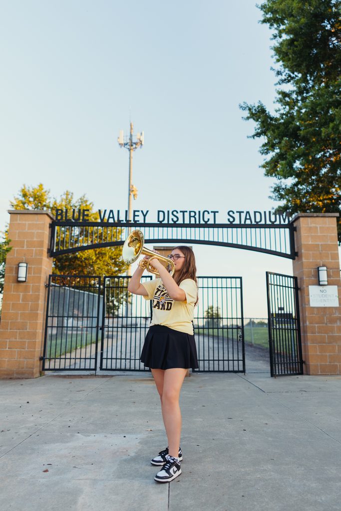 Kansas City senior pictures featuring her trumpet on the football field at sunset